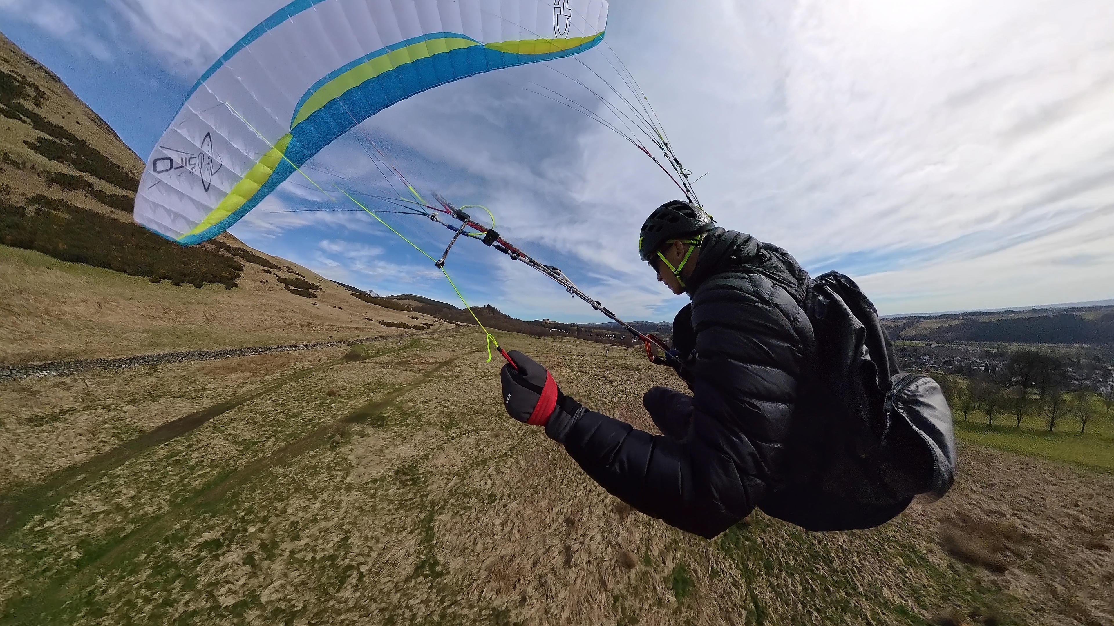 Paraglider preparing to fly over a hillside.